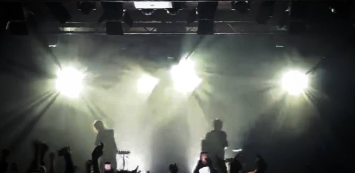 Concert stage lighting with bright backlights and silhouettes on stage.